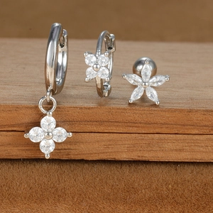 Detail of silver earring set featuring zircon flowers and moon on a brown velvet surface