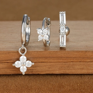 Macro detail of three-piece silver earring set with zircons on wooden display