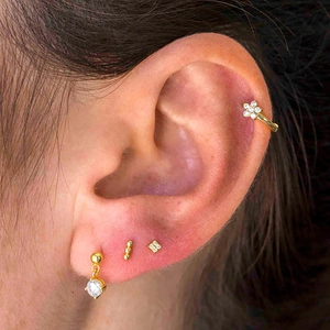 Detail of gold-plated star and floral zirconia earrings set for multiple piercings