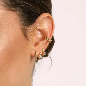 Close-up of gold ear cuff and hoop earrings with star and flower crystal pendants