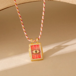 Détail d'un pendentif tarot avec œil en émail rouge et zircons sur cordon tressé
