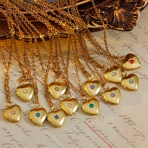 Vintage gold heart locket necklace with colorful birthstones on retro script paper