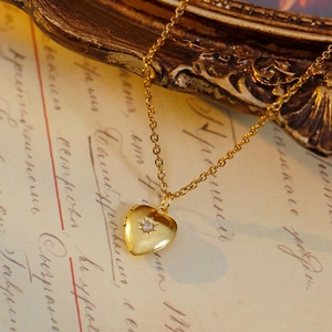 Macro shot of gold heart locket with white zircon starburst inlay on vintage background