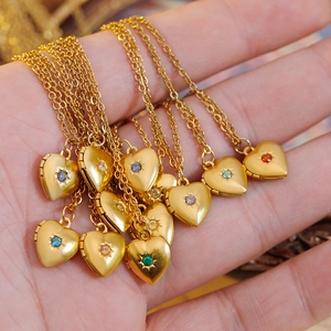Golden heart locket necklace with colorful birthstones held in hand for Mother's Day