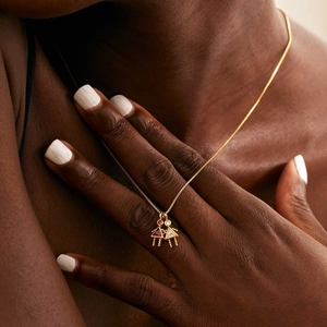 Gold chain necklace featuring two girl pendants with red and white triangular zircons