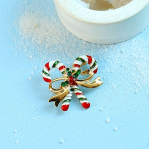 Christmas candy cane brooch with gold bow and red crystals on blue background