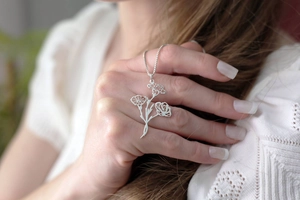 Gros plan d'un collier pendentif floral argenté évidé avec des détails de roses et de feuilles