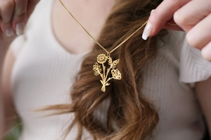 Gros plan d'un collier bouquet plaqué or avec détails floraux de tournesol et rose