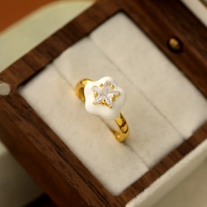 Détail d'une bague fleur dorée avec un zircon en forme d'étoile dans un écrin en bois
