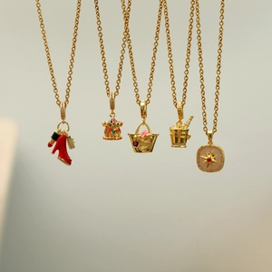 Detailed macro view of five gold-plated necklaces with enamel high heels and charms
