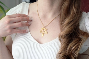 Détail du collier avec pendentif bouquet doré 18 carats porté par un mannequin sur un haut
