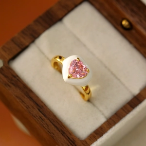 Détail d'une bague ajustable dorée avec cœur en zircon rose et émail blanc incrusté