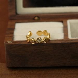 Détail de la bague coquillage dorée 18K et zircons sur une boîte à bijoux en bois
