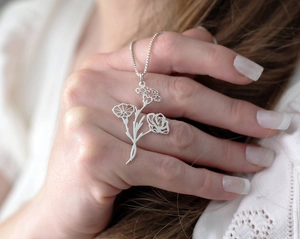 Vue détaillée de trois breloques florales reliées sur un collier argenté délicat