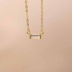 Macro detail of gold necklace with rectangular translucent gemstone pendant on skin