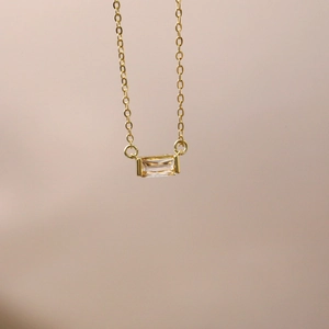 Detailed close-up of golden birthstone necklace featuring a rectangular zircon pendant