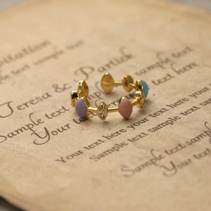 Détail d'une bague dorée ajustable avec cristaux marquise colorés sur papier rétro