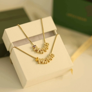 Detail of gold Mama necklaces with purple and yellow birthstones in a gift box
