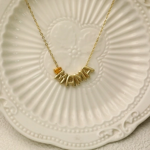 Golden MAMA necklace with a yellow teardrop gemstone pendant on a refined cross chain