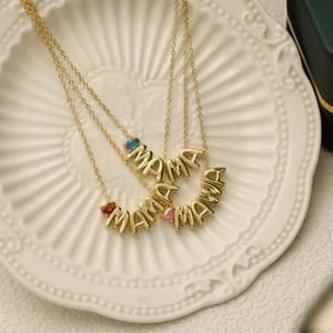Close-up of gold MAMA necklaces with colorful teardrop birthstones on a white plate