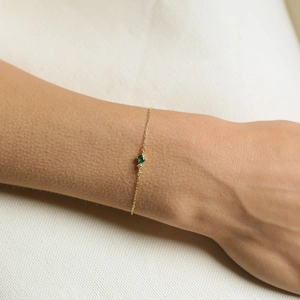Minimalist 18K gold chain bracelet featuring a green birthstone and a small diamond