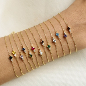Vintage style gold chain bracelets with various colorful birthstones on a model arm