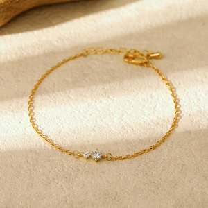 Detail of gold thin chain bracelet with two sparkling zircons and lobster clasp closure
