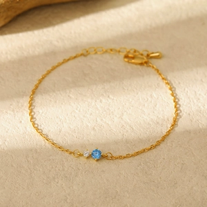 Detail of 18K gold birthstone bracelet with sparkling blue and white round gemstones