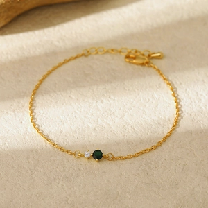 Detailed macro shot of vintage gold bracelet with sparkling white and emerald green stones