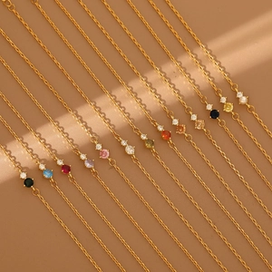 Detail view of gold chains with diverse birthstones and subtle window shadow patterns