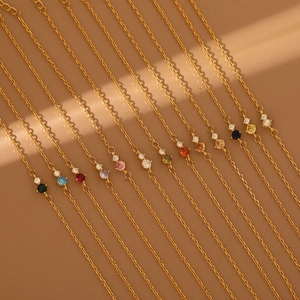 Macro detail of twelve gold birthstone bracelets featuring colorful gems and natural light