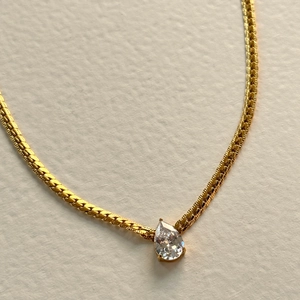 Elegant gold flat snake chain necklace with a pear-cut clear zircon teardrop pendant