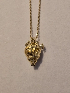 Dettaglio di una collana con ciondolo a cuore anatomico dorato con texture realistiche