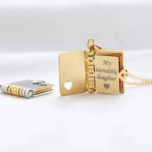 Detail of gold book locket with My Incredible Daughter engraving and heart charm