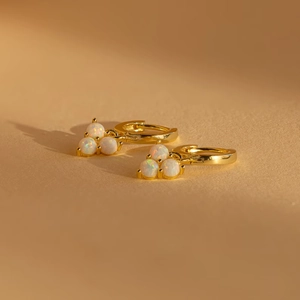 Detail of 18K gold plated hoop earrings with iridescent opal clusters in warm lighting