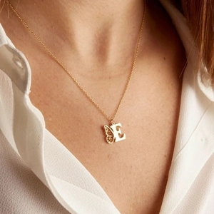 Collier doré en acier inoxydable avec lettre E et aile de papillon porté par un mannequin