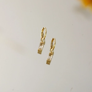 Detail von goldenen Sternohrringen mit rechteckigem Zirkonia und elegantem Klickverschluss