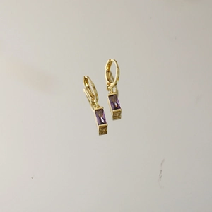 Detailansicht der goldenen Creolen mit eleganten rechteckigen lila Edelsteinen