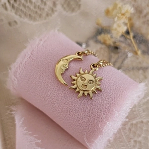 Colliers célestes vintage avec pendentifs soleil et lune posés sur un ruban de soie rose