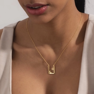 Gros plan détaillé d'un pendentif rectangulaire doré avec soleil et lune sur une femme