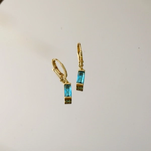 Detailansicht der goldenen Brisur-Ohrringe mit smaragdgeschliffenen blauen Edelsteinen