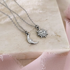 Ensemble de colliers pendentifs soleil et lune en argent sur socle en pierre