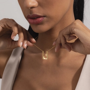Collier en acier doré avec pendentif soleil lune et motif méandre grec porté par mannequin