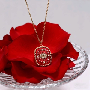 Detail eines roten Emaille-Anhänger Böser Blick mit Strass auf roten Rosenblättern