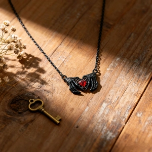Dettaglio macro della collana gotica con mani di scheletro che tengono un cuore rosso