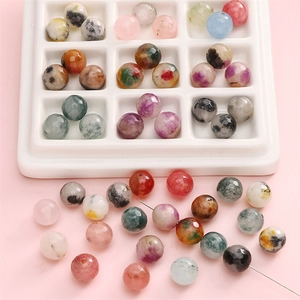 Faceted natural stone beads in assorted colors displayed in a white ceramic grid tray