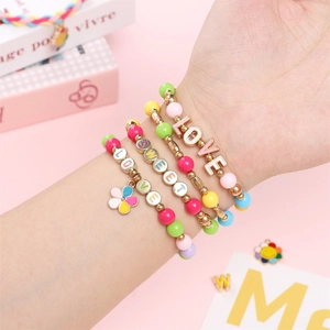 Detail von vier bunten Acrylperlenarmbändern mit LOVE- und SWEET-Anhängern am Handgelenk