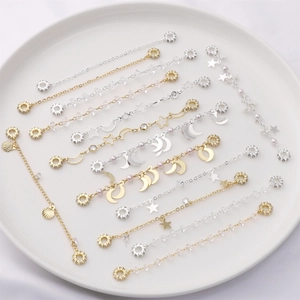 Star and moon pearl bracelet with gold and silver chain designs on a white plate