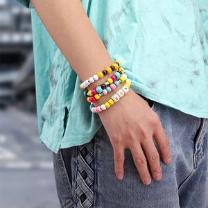 Detail von mehrlagigen Boho-Perlenarmbändern mit SUN-Buchstabenanhänger am Handgelenk