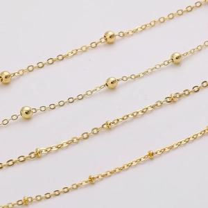 Macro shot of gold-plated copper chain extensions and textured beads for DIY jewelry